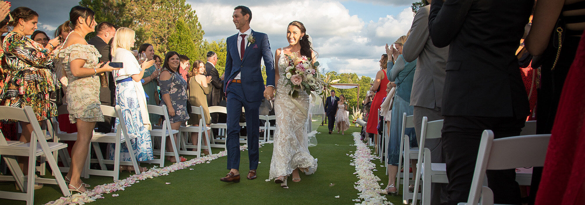 bride and groom outfitted by j&a custom clothing walking down the aisle