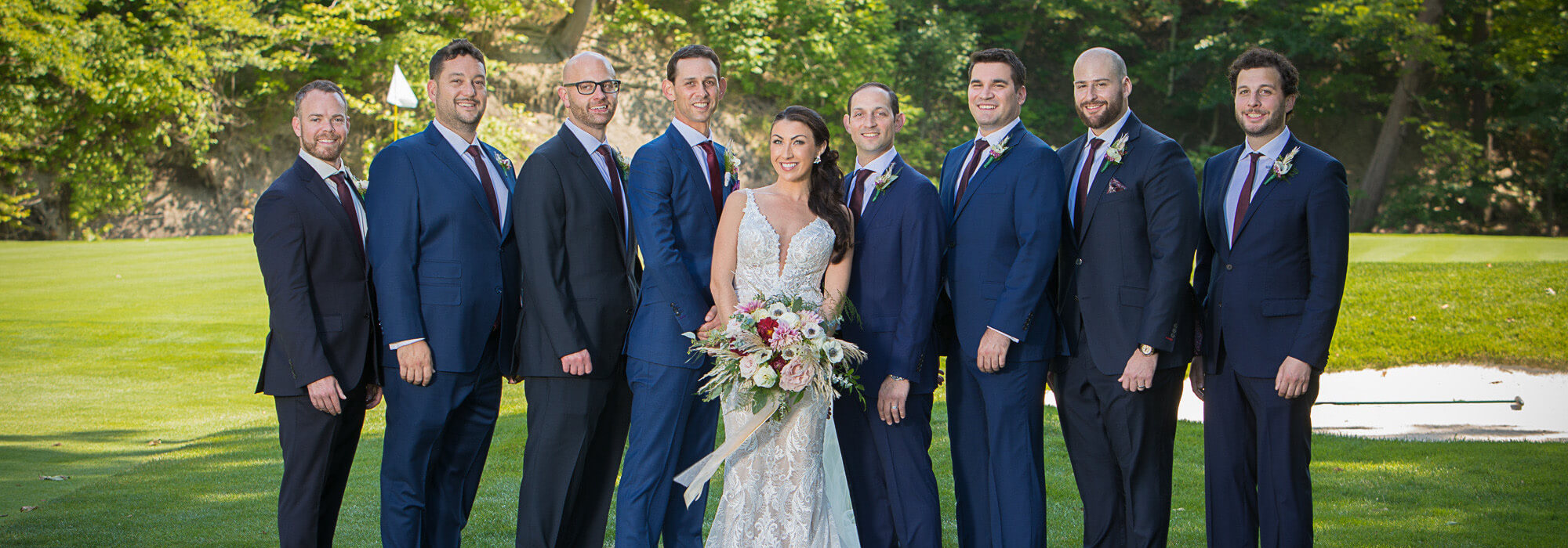 bridal party with groomsmen wearing custom suits